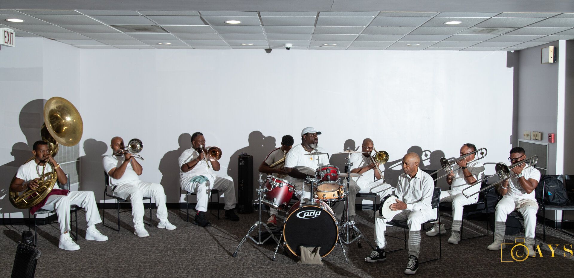 Large brass band ensemble of musicians in white attire and hats performing together at a community banquet