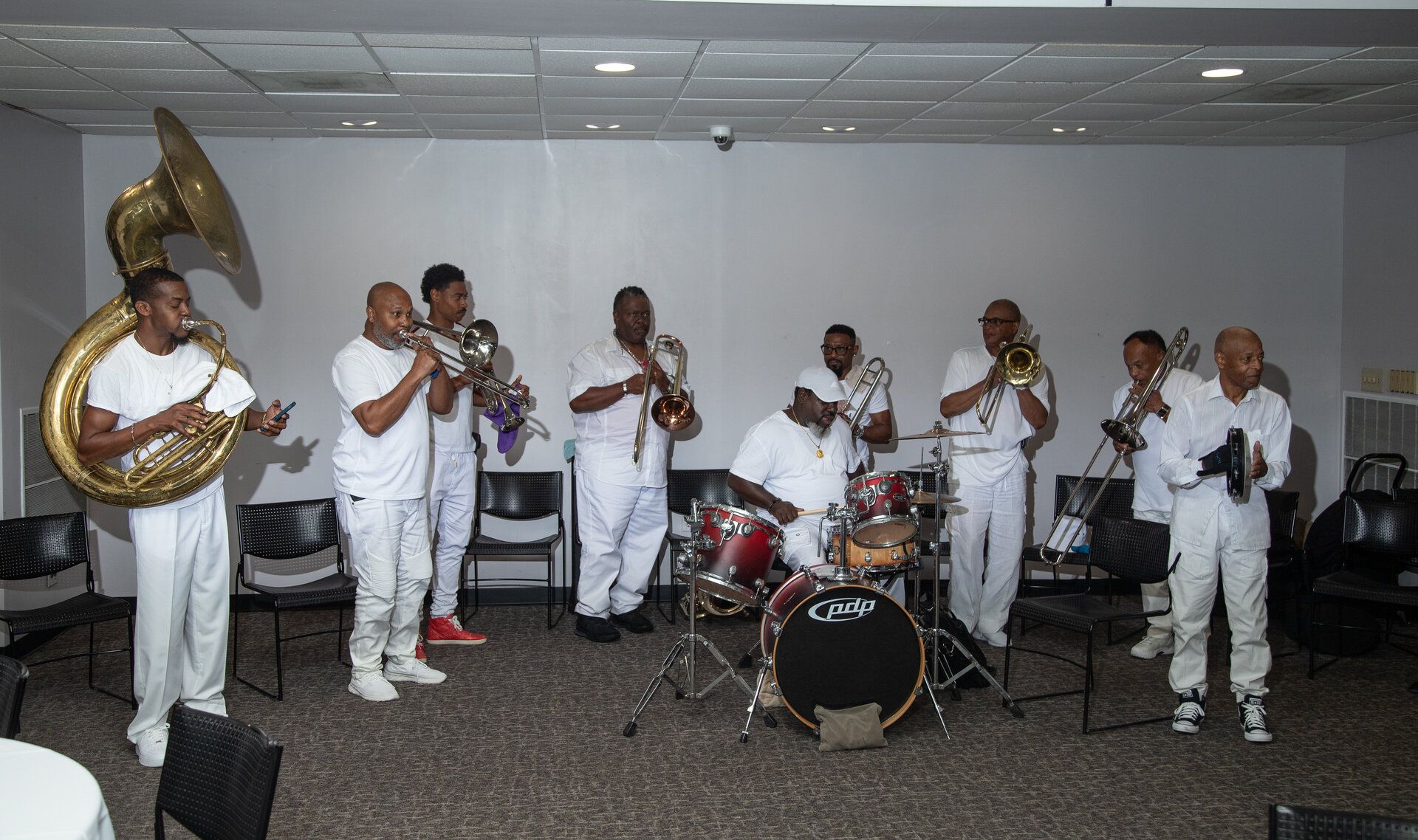Large brass band ensemble in white attire performing with tubas, trumpets, and drums at the Jamestown Foundation Festival Banquet