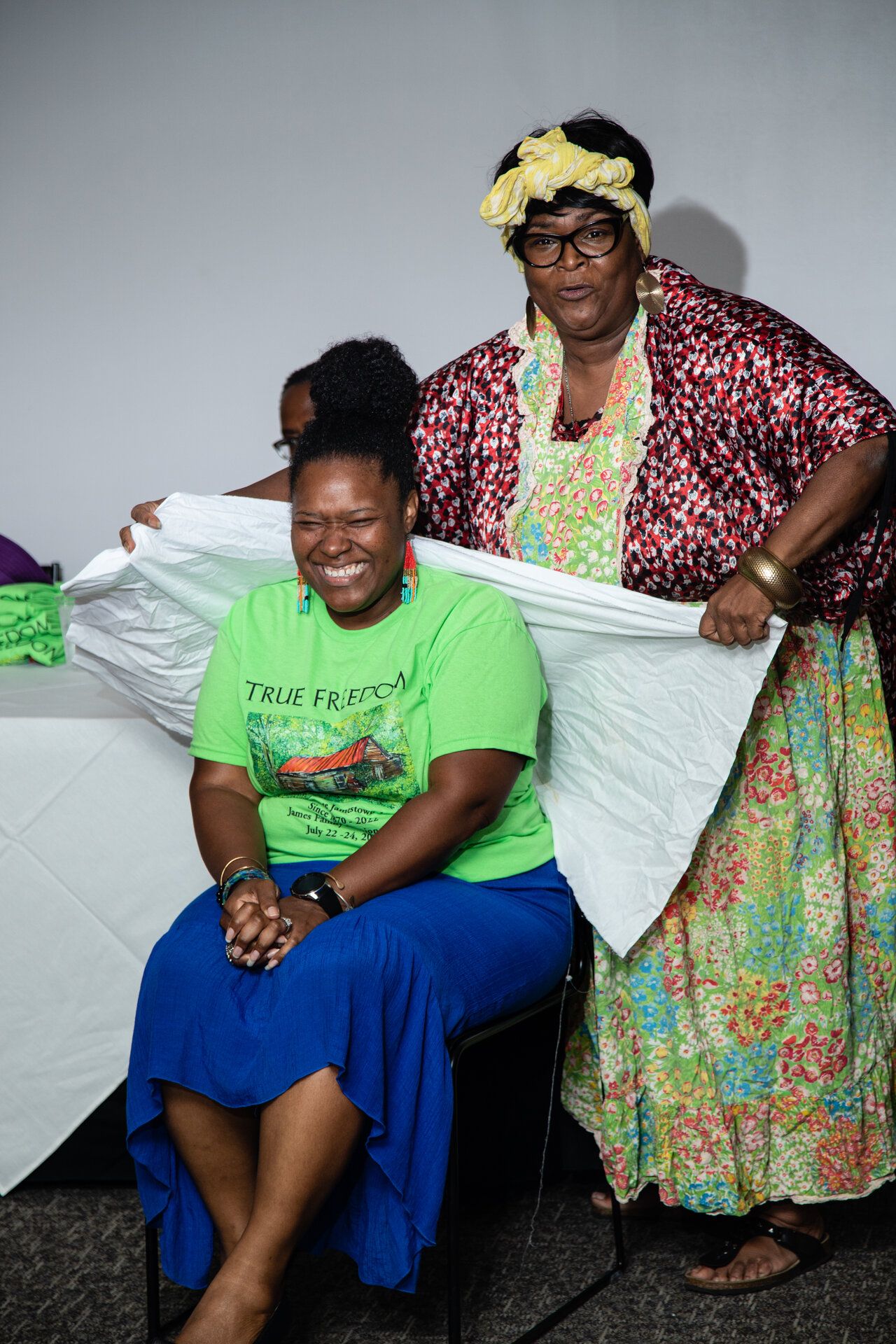 Older woman in colorful outfit warmly embracing a seated younger woman in a beautiful intergenerational bonding moment