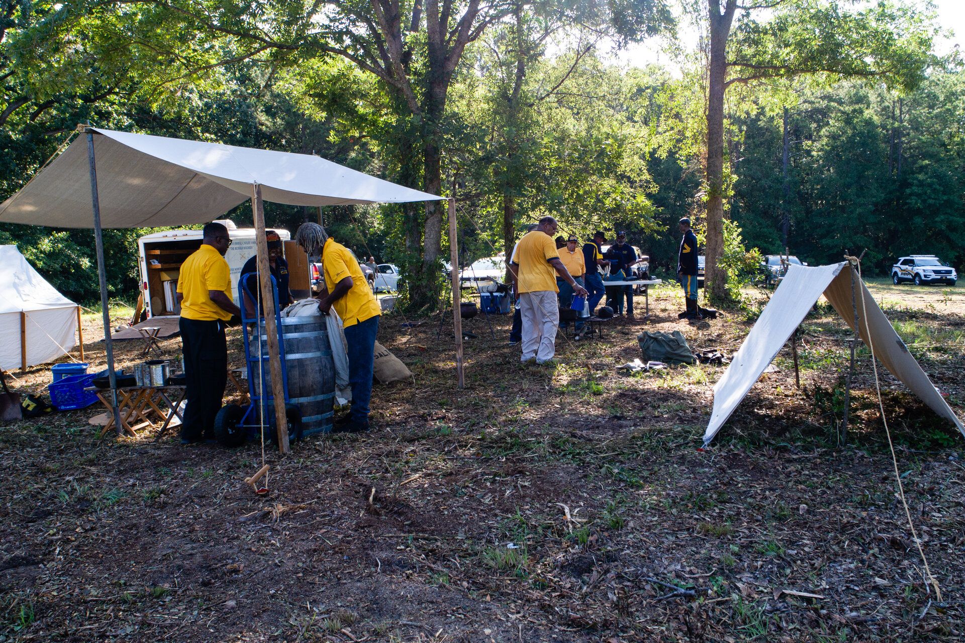 Volunteers in yellow festival shirts gathered under a white tent conducting activities at the Celebrate Jamestown Festival